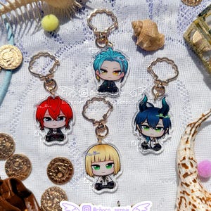 Può includere: Quattro portachiavi in acrilico raffiguranti personaggi anime in stile chibi con capelli di colori diversi: rosso, turchese, biondo e blu scuro con corna. Ogni ciondolo è fissato a una chiusura dorata a forma di conchiglia con testo.