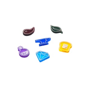 May include: Six colorful glass tokens with different symbols: a red teardrop, a green leaf, a blue anvil, a yellow slice of bread, a purple potion bottle, and a blue diamond.