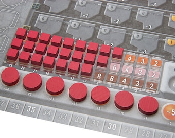 Op de afbeelding: Een close-up van een spelbord met rode en bruine plastic fiches. Het bord heeft nummers van 28 tot 27 en -30 tot -5. De fiches zijn in een rij gerangschikt en worden gebruikt om punten in het spel bij te houden.