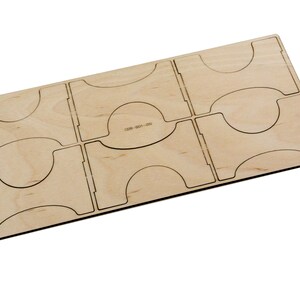 May include: A wooden organizer with six compartments for holding game cards or other small items. The organizer is made of light brown wood and has a smooth finish.