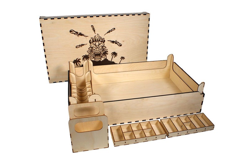 May include: Wooden box with a laser-cut design of a tiki head with flames and palm trees on the lid. The box has dividers and trays for organizing game pieces.
