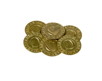 May include: A pile of six gold-coloured metal tokens with the letter "C" and the words "The Culinarian" on each token.