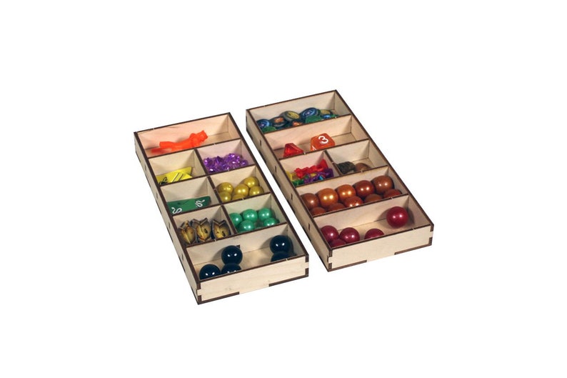 May include: Two wooden organizer trays with compartments for storing game pieces. The top tray has a variety of colored plastic game pieces, dice, and tokens. The bottom tray has black and green game pieces.