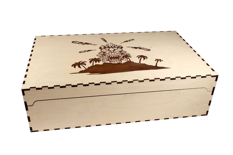 May include: A wooden box with a brown tiki head design on the lid. The box has a black and white checkered border around the edge.