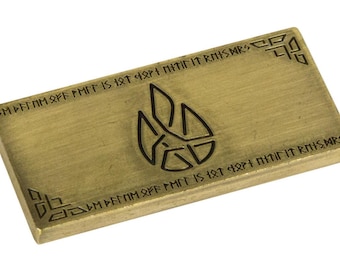 May include: A gold-colored metal rectangular plaque with a black symbol and text in a stylized font. The text reads "CMPFTOM OFF PMIT IS 18T 4ΩΡΗ NITIN IT RMIS MRSP".