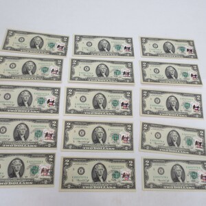 May include: A collection of twenty $2 bills featuring Thomas Jefferson. The bills are arranged in rows of three, with the top row slightly offset from the others. The bills are all in good condition and have a green tint.
