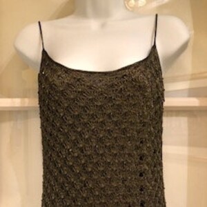 May include: A sleeveless dress featuring a dark bronze, metallic, open-knit mesh overlay with a subtle diamond pattern. The garment has thin spaghetti straps, a scoop neckline, and a straight-cut silhouette that falls from the shoulders.