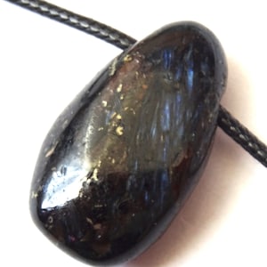 May include: A dark blue, smooth, oval-shaped pendant with a black cord. The pendant has a metallic sheen and a subtle shimmer.