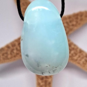 Può includere: Un ciondolo a forma di lacrima di opale blu chiaro con un cordoncino nero.