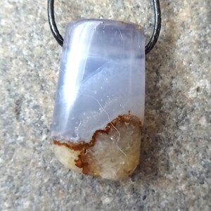 May include: A rectangular pendant with a blue and white marbled pattern, featuring a brown and tan base. The pendant is suspended from a black cord, showcasing a natural stone design.