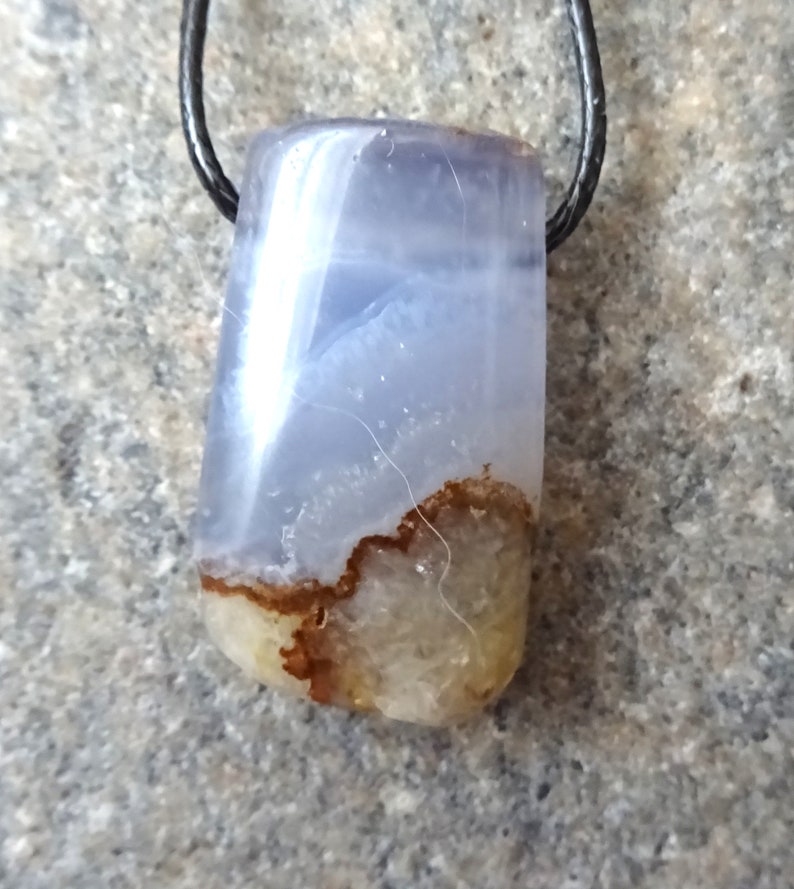 May include: A rectangular pendant with a blue and white marbled pattern, featuring a brown and tan base. The pendant is suspended from a black cord, showcasing a natural stone design.