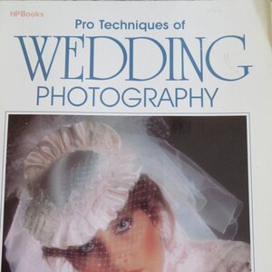 May include: A book cover with the title "Pro Techniques of Wedding Photography" in blue text on a white background. The cover features a photo of a bride wearing a white veil and a white hat with lace trim. The bride is looking down with her eyes closed. The text "Robert & Sheila Hurth" is printed in black at the bottom of the cover.