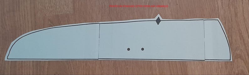 May include: A light blue, paper-based template with a black outline. The template is segmented into three rectangular sections and one curved section. Two small black dots and a diamond shape are visible.