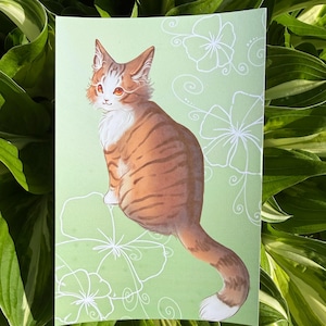 May include: A print featuring a seated orange tabby cat with white markings, set against a light green background with white floral outlines. The cat has orange eyes and a fluffy tail. The artwork is a whimsical illustration.