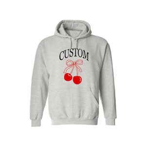 May include: A gray hooded sweatshirt with the word "CUSTOM" printed in black and a red cherry with a bow on top.
