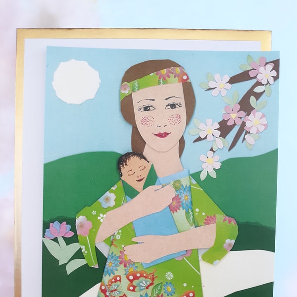 Une carte plate 5x7 avec une mère portant un kimono et tenant un enfant enveloppé dans le bleu dans un jardin fait avec du papier coloré et du papier origami.