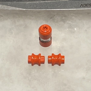 Puede incluir: Tres ruedas de patines en línea de plástico naranja. Las ruedas están diseñadas para patines en línea y tienen un eje de metal.