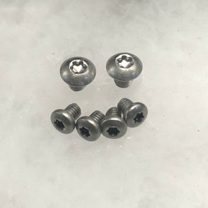May include: A set of seven silver-toned screws with a star-shaped head.