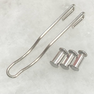 May include: A silver-toned metal belt clip with a curved, elongated shape and three matching silver-toned metal screw-post fasteners. The components are made of polished metal and feature a smooth, reflective surface finish throughout the set.
