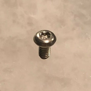 Puede incluir: Un tornillo plateado con cabeza hexagonal y cabeza Phillips.