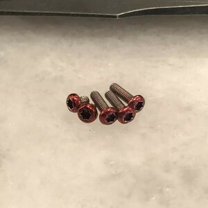 May include: Five silver screws with red star-shaped heads.