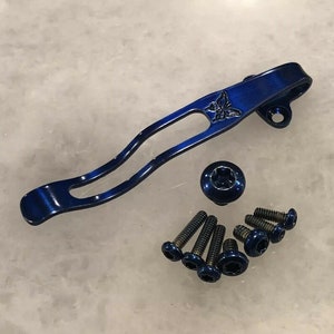 Puede incluir: Un clip de bolsillo de titanio azul con un diseño de mariposa y seis tornillos azules.