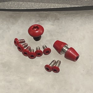Peut inclure: Un assortiment de vis et fixations peintes en rouge. L'ensemble comprend différentes tailles et formes, avec des modèles à tête plate et à tête arrondie. Les composants métalliques ont une finition rouge vif.
