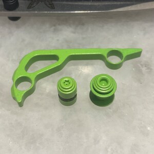 May include: A set of three lime green 3D printed parts for a video game controller. The parts include a trigger, a button, and a thumbstick.