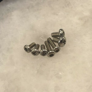 May include: A group of ten silver-toned screws with a star-shaped head.