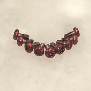 Puede incluir: Primer plano de diez pequeños tornillos rojos en forma de estrella.