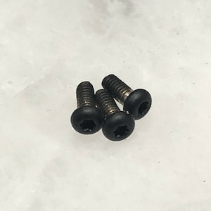 May include: Four black screws with a star-shaped head and a black plastic cap.