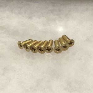 May include: A close-up of ten gold-colored screws with a star-shaped head.