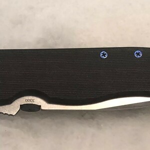 May include: A black pocket knife with a partially open blade and blue screws. The knife has a textured handle and the number "3300" is engraved on the handle.