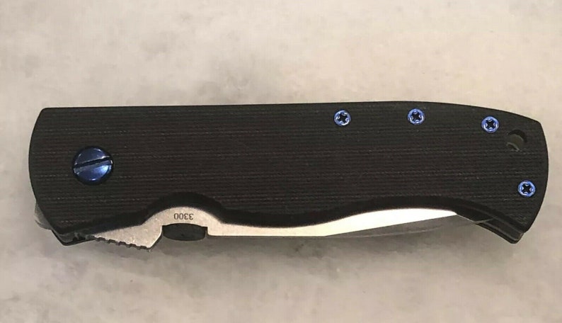 May include: A black pocket knife with a partially open blade and blue screws. The knife has a textured handle and the number "3300" is engraved on the handle.