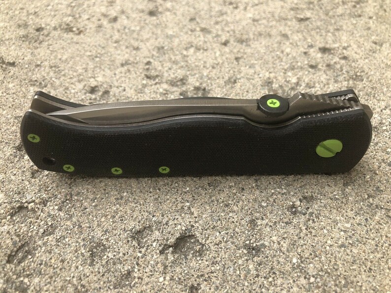 May include: A black pocket knife with a green accent on the handle and a partially open blade.