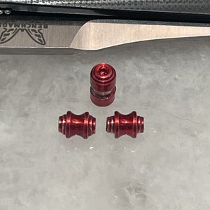 Peut inclure: Trois perles en métal rouge, deux sont cylindriques et une est ronde. Les perles ont une finition brillante.