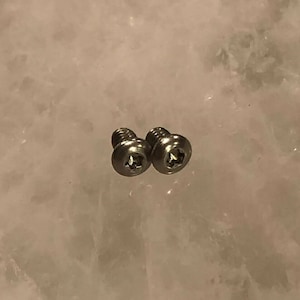 Puede incluir: Dos tornillos plateados con cabeza de estrella.