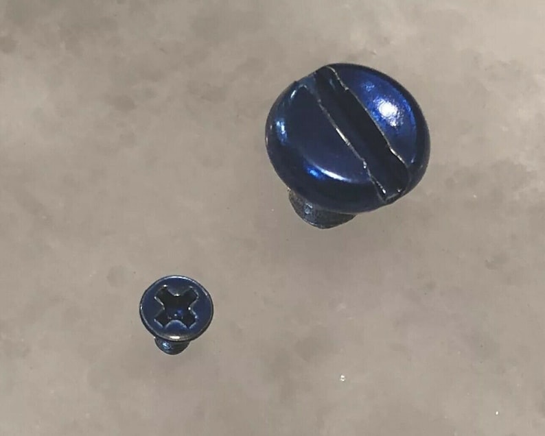 May include: Two blue screws of different sizes. The larger screw has a slotted head, while the smaller screw has a Phillips head. Both screws have a shiny, metallic finish and are set against a light-colored background.