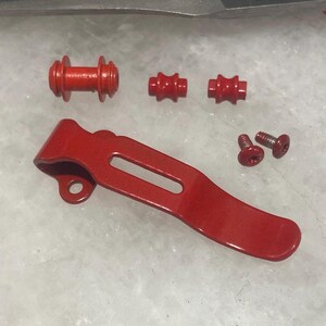 May include: Red metal pocket clip with two red plastic spacers and two red plastic barrel spacers, and two silver screws.