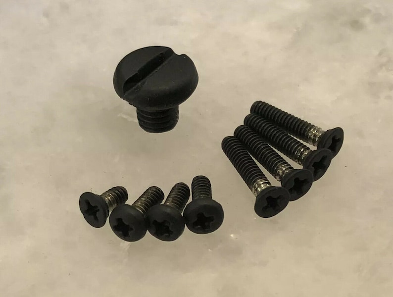 May include: A set of black screws with a Phillips head and a black plastic screw with a slot head.