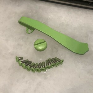 Pode incluir: Um conjunto de ferragens de metal verde para uma faca, incluindo um espa&ccedil;ador traseiro, um clip de bolso e 12 parafusos.