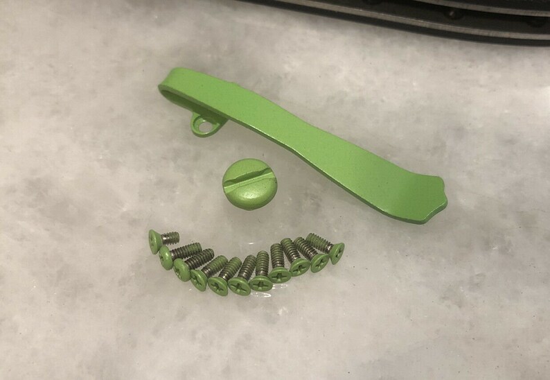 Pode incluir: Um conjunto de ferragens de metal verde para uma faca, incluindo um espa&ccedil;ador traseiro, um clip de bolso e 12 parafusos.