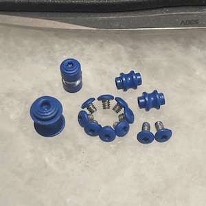 May include: A set of blue screws and bolts, including a larger bolt with a blue plastic cap. The screws have a star-shaped head and are arranged in a circle.