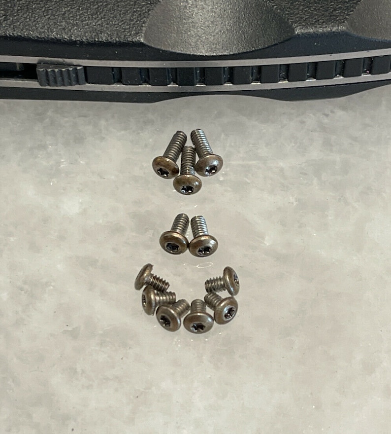 May include: A collection of ten small, bronze-colored screws with a star-shaped head.