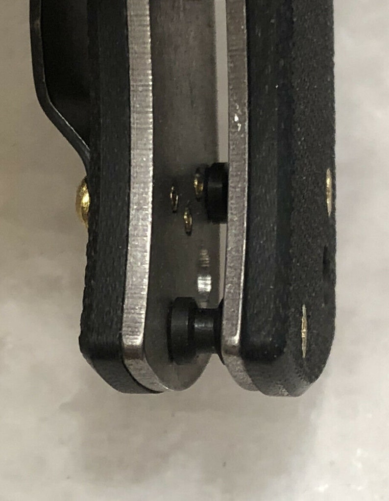 May include: Close-up of a black and silver pocket knife with a black handle and a silver blade. The knife has a pocket clip and a small gold screw.