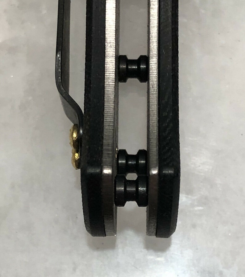 May include: Close-up of a black pocket knife with two silver pivot pins. The knife has a black handle and a silver blade.