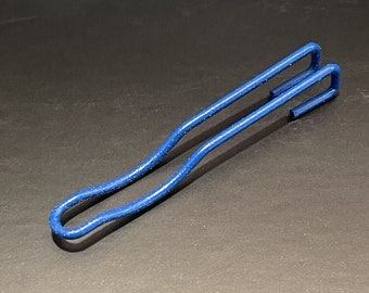 May include: A blue metal clip with a unique curved design. The clip is made of two pieces of metal that are joined together at the top and bottom.