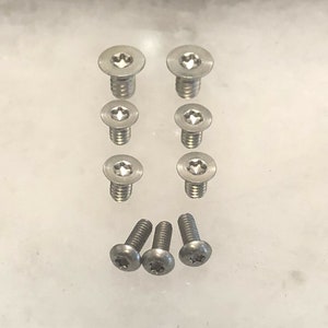 Puede incluir: Un juego de diez tornillos plateados con cabeza de estrella. Los tornillos están dispuestos en dos filas de cinco.