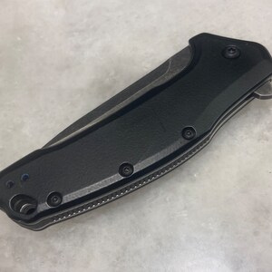 May include: A black folding knife with a textured handle and a partially serrated blade.