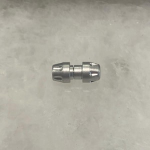 May include: A silver metal connector with a ridged design on each end.